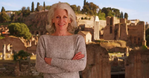 腕を組んでローマ時代の遺跡の前に立って幸せな先輩女観光 — ストック写真