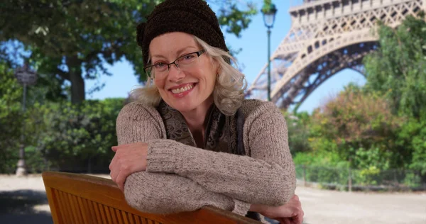 愉快的微笑的老妇女游客坐在公园长凳在巴黎的埃菲尔铁塔 — 图库照片