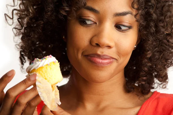 Tight shot of millennial woman tempting to eat sweet cup cake