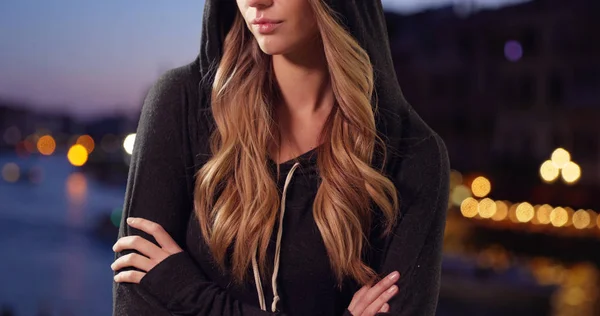 Attractive blonde female wearing a hoodie outside in evening