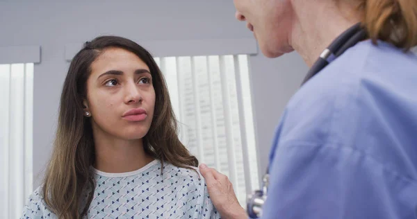 Enfermera Mediana Edad Reconforta Joven Paciente Latina Usando Bata Hospital — Foto de Stock