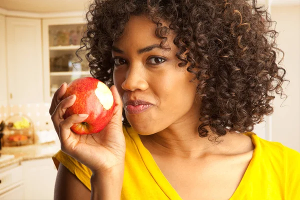 住宅厨房内の新鮮な赤いリンゴを食べる若い黒人女性の肖像画 — ストック写真