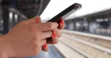 Genç kadın manifatura metro platformda akıllı telefon ile profil kapatın