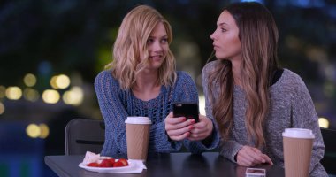 İki sevimli kız hücre kullanarak telefon resimler Paris'te açık havada bakmak Fransa