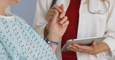 Olgun kadının elini tutarak hastanede doktor