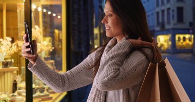 Güzel müşteri telefon selfie torbaları üzerinde şehir taşırken geceleri sokak alır