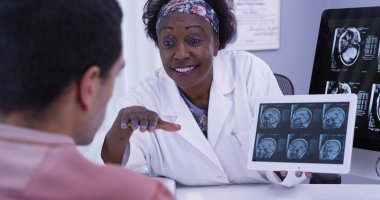 Kadın doktor genç latino hasta sonuçları için MRI açıklayan closeup