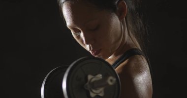 Dumbell ağırlık kaldırma ve terleme etkin Asyalı kadın