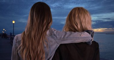 İki kadın arkadaş dost birlikte iskele alacakaranlıkta paylaşmak
