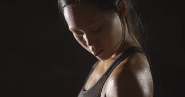 Dumbell ağırlık kaldırma ve terleme etkin Asyalı kadın