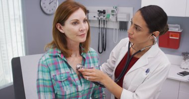 Güzel genç latina Doktor stetoskop üst düzey hastalar hayati incelemek için kullanarak