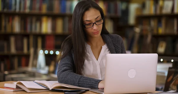 Latina college student works on laptop at the library