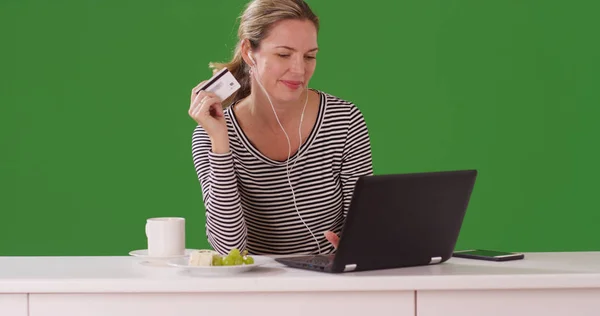 Caucasian woman making purchase on laptop with credit card on green screen