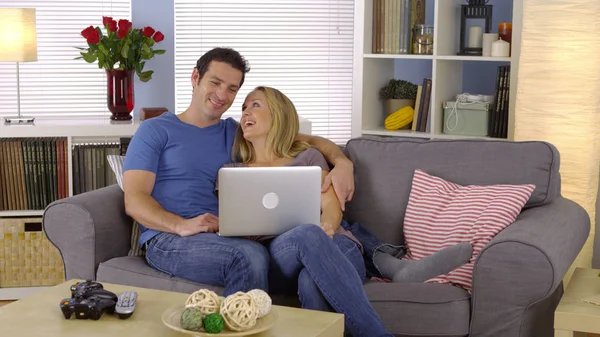 愉快的夫妇坐在沙发上与笔记本电脑 — 图库照片