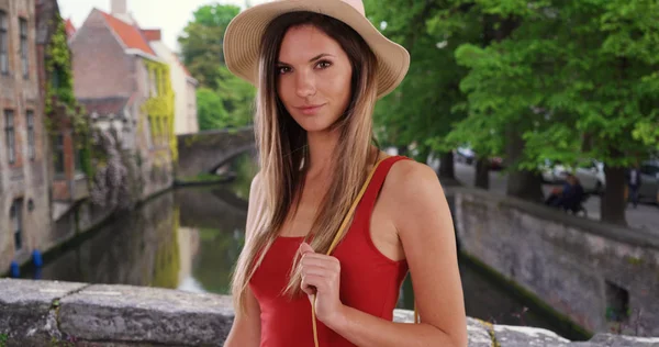 Stylish white woman holding purse smiling at camera outside in Bruges Belgium