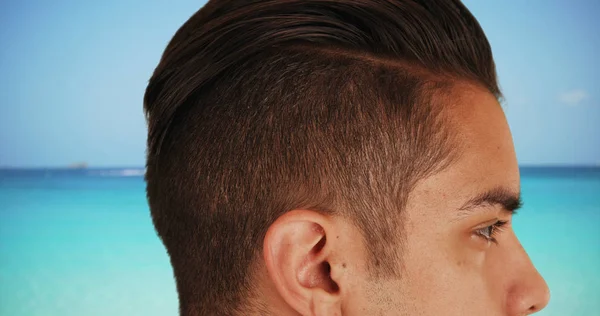 Close up of handsome Latin male with cool undercut standing by ocean