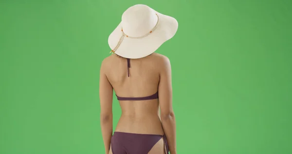 Rear view of black girl in bikini and sun hat on green screen