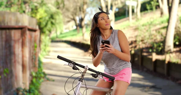 Smiling Latina Female Sitting Bicycle Sunny Park Messaging Cellphone — Stock Photo, Image