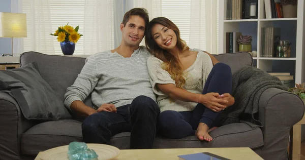 有吸引力的混合种族夫妇坐在沙发上微笑 — 图库照片