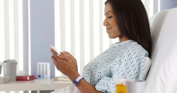 在病床上使用智能手机的黑人妇女 — 图库照片