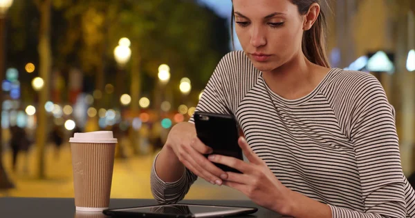 パリのシャンゼリゼのカフェ テーブル テキスト メッセージ携帯電話で座っている若い女性 — ストック写真