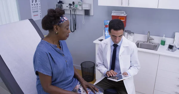 漂亮的拉丁医生使用便携式平板电脑查看患者的健康史 — 图库照片