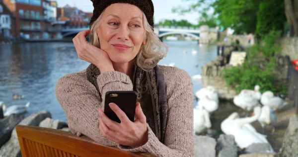 Senior Vrouw Bankje Door Rivier Windsor Kijken Naar Mobiele Telefoon — Stockfoto