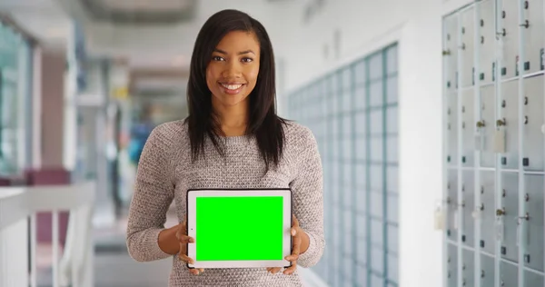 Attractive black female at post office holding blank tablet with green screen