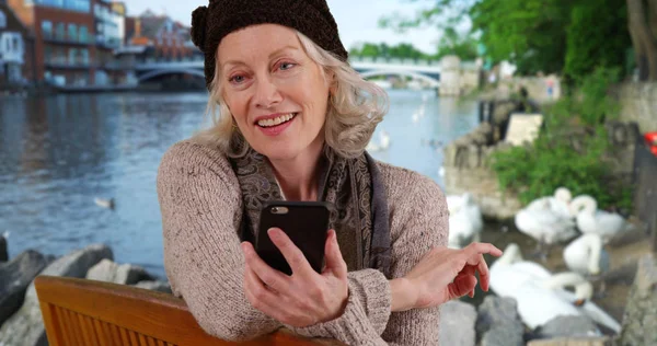 Senior Vrouw Bankje Door Rivier Windsor Kijken Naar Mobiele Telefoon — Stockfoto