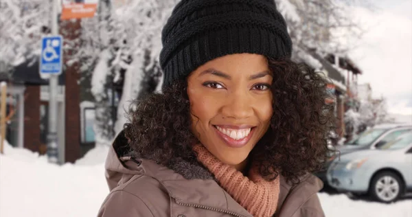 Upbeat young African-American lady posing happily in small town in the winter