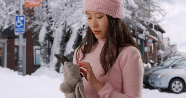 Close up of Asian millennial using smartphone in snowy old town California