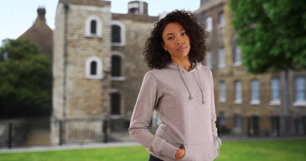 Black millennial woman on vacation in England wearing a grey hoodie