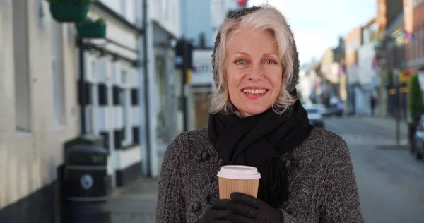 セーターとスカーフの街で紙のコーヒー カップを保持している幸せな先輩女 — ストック写真