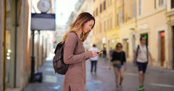 Pretty Caucasian woman on Roman street using map on cellphone