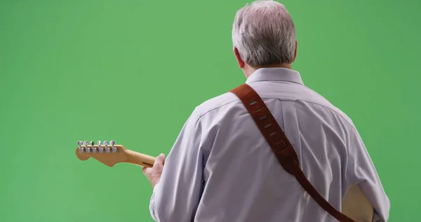 Rear view of mature white male playing electric guitar on greenscreen