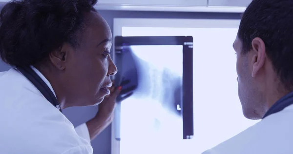 Close-up of mid aged doctor reviewing patient x ray with young radiologist