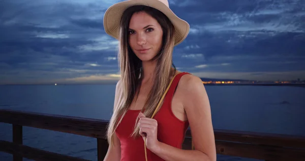 Stylish white woman holding purse smiling at camera while standing on pier