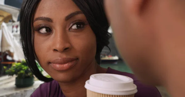 Casual attractive black woman listens intently to boyfriend over coffee
