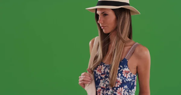 Millennial woman in floral print romper wearing fedora on greenscreen