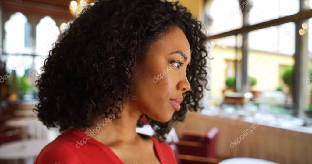 Young black lady deep in thought inside restaurant setting
