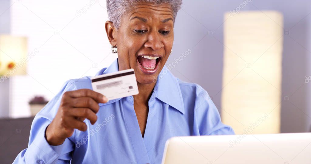 Happy Mature Black woman typing in card information