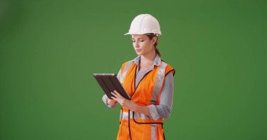 Yeşil ekranda tablet aygıtı kullanarak genç kadın inşaat müdürü