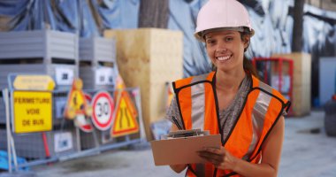 Kadın inşaat işçisi kask ve şantiye kameraya gülümseyen yelek