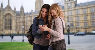 Sosyal medya birlikte telefonla tarama iki beyaz kız Westminster Palace yakınındaki oteller