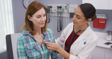 Güzel genç latina Doktor stetoskop üst düzey hastalar hayati incelemek için kullanarak