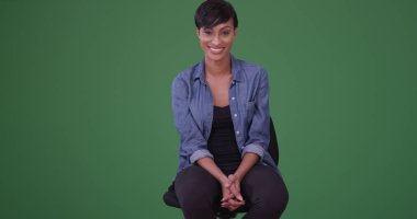 Portrait of a young african american woman smiling at the camera on green screen clipart