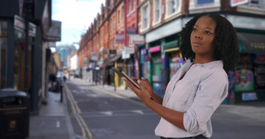 Londra'nın yenilikçi görünümlü mahallede tablet kullanarak çekici siyah kadın