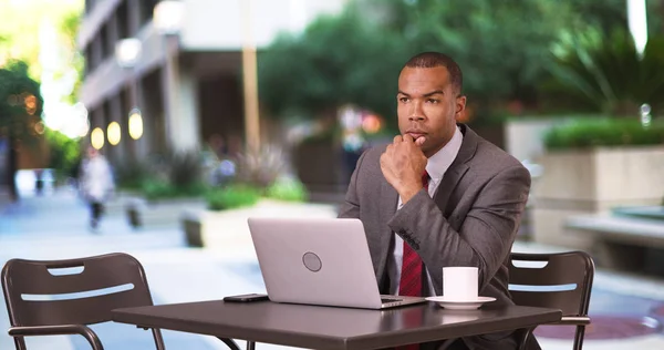 一个黑人商人一边喝咖啡一边用他的笔记本电脑工作 — 图库照片