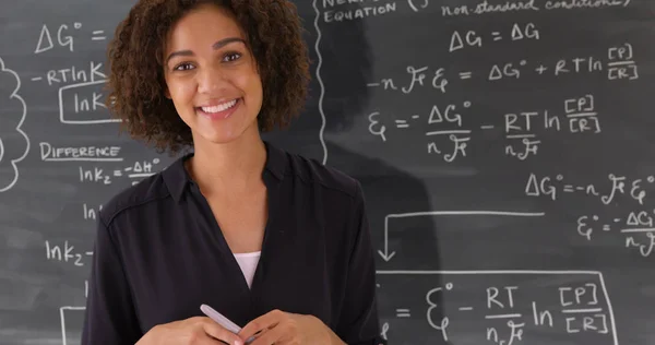 Portrait of black teacher giving math lesson on chalkboard