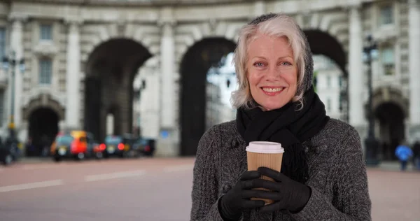 寒い秋の日の熱い一杯のコーヒーを保持しているロンドンの観光客を幸せな年配の女性 — ストック写真